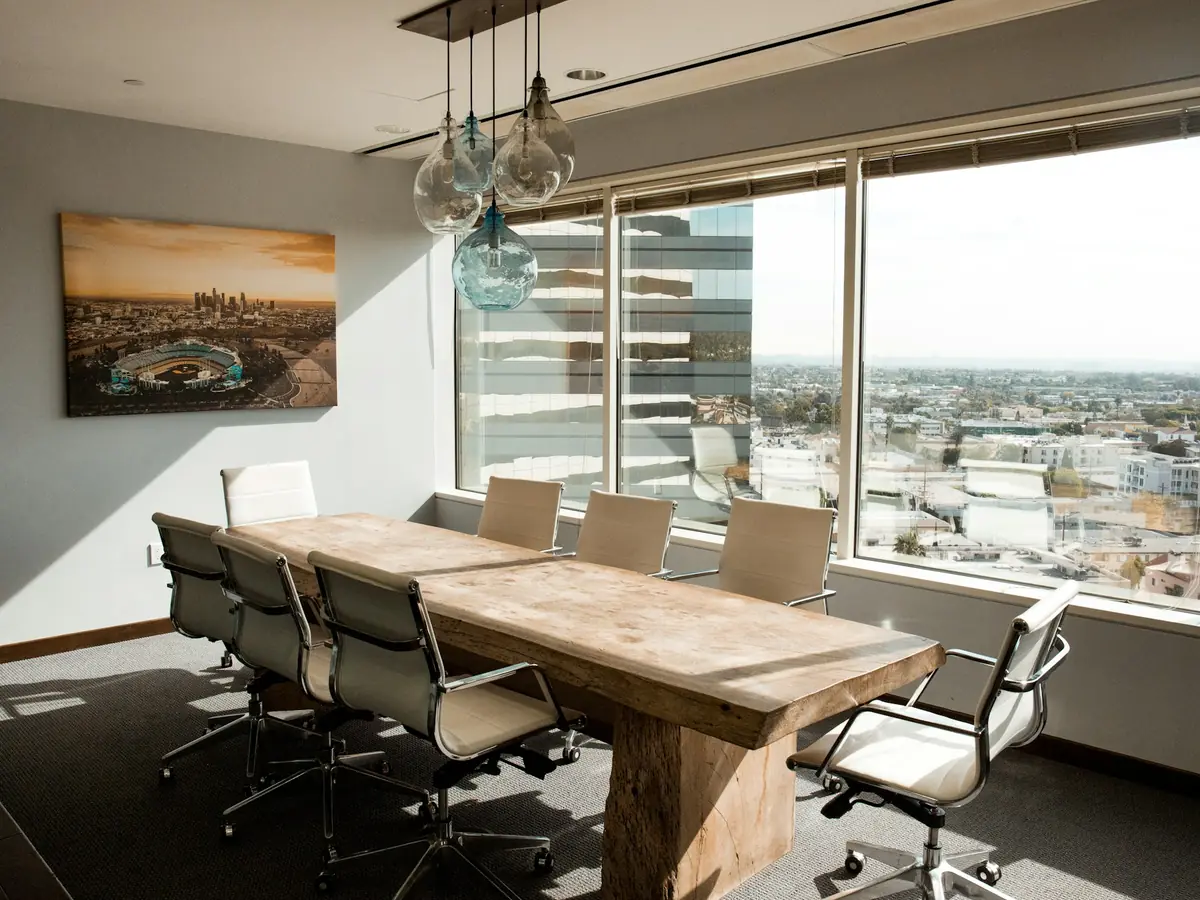 Sala de juntas vacía con mesa de madera y vista a la ciudad
