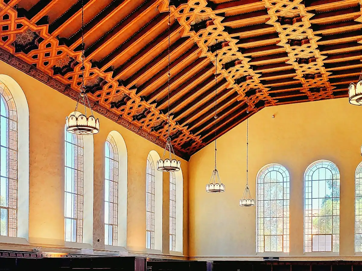 Sala de lectura con ventanales en arco y techo de madera